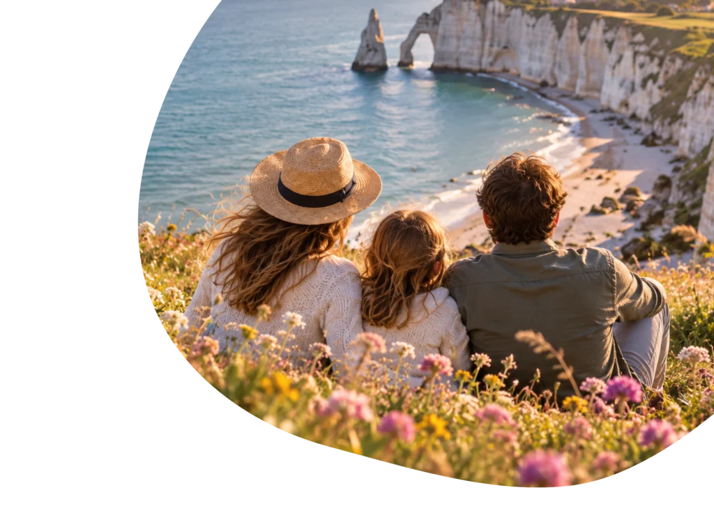 Une famille est assise sur une falaise herbeuse surplombant la mer et les falaises de craie blanche d'Étretat, une destination incontournable pour tout amateur de voyages.